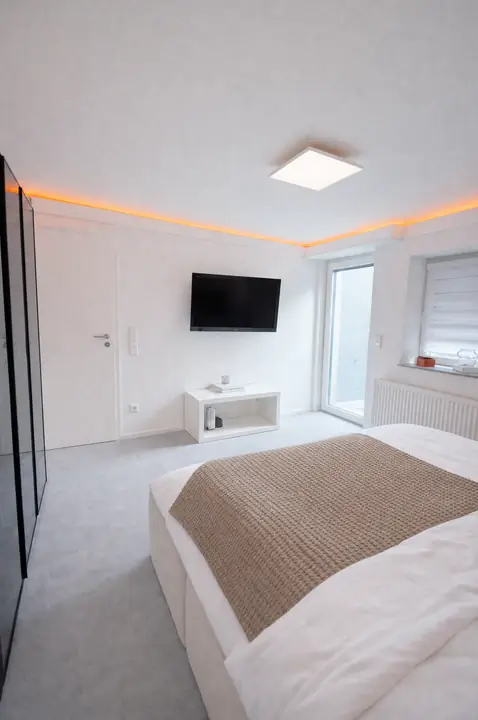 Schlafzimmer mit Fernseher, Kleiderschrank und Zugang nach draußen
