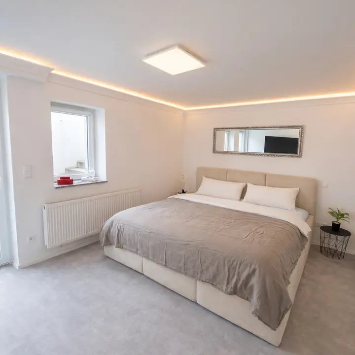 Schlafzimmer mit Doppelbett und indirekter Deckenbeleuchtung