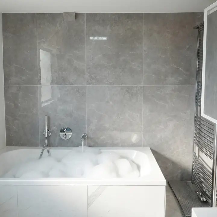 Badewanne mit Schaum vor grauer Steinwand