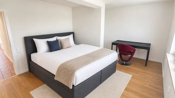 Schlafzimmer mit Boxspringbett und Schreibtisch