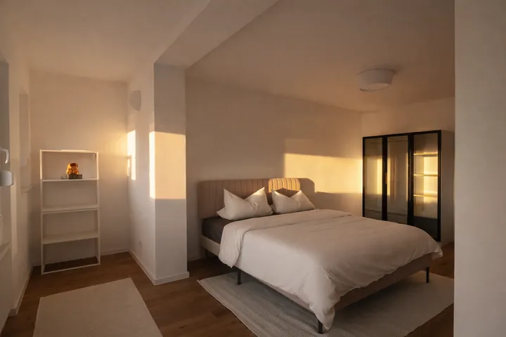 Schlafbereich mit Doppelbett und Glasvitrine im Abendlicht